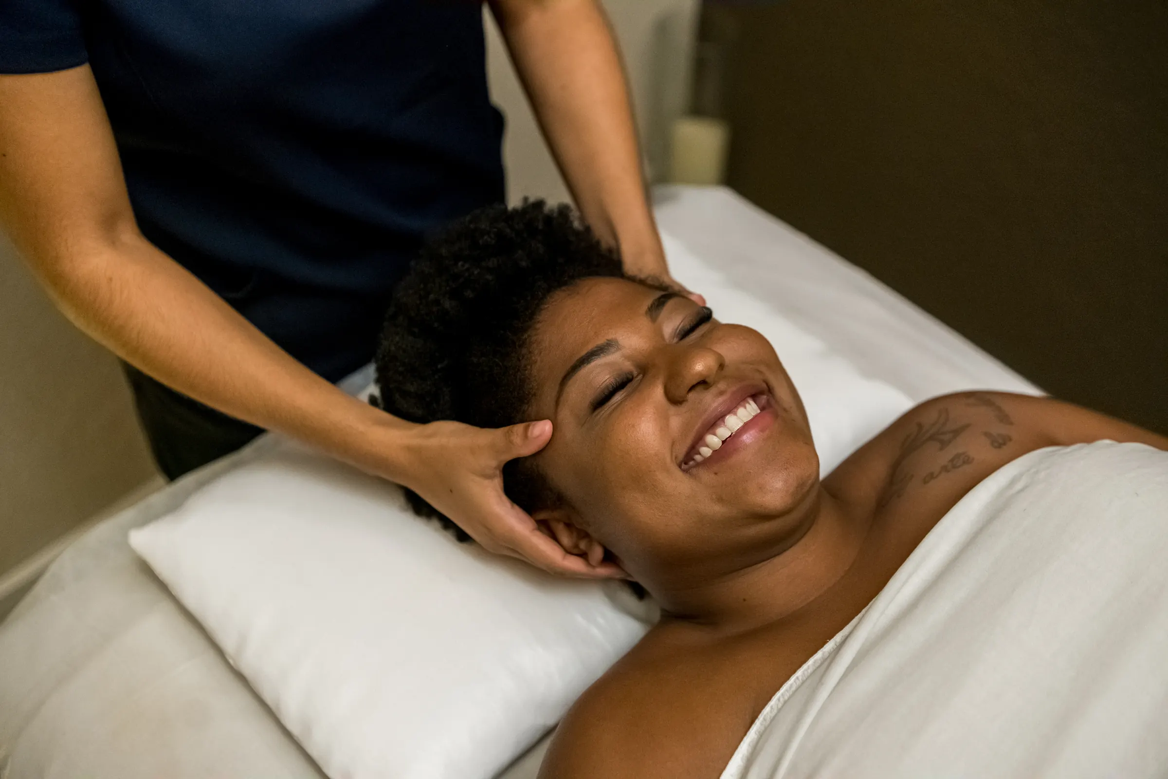 Cliente sorrindo durante massagem no couro cabeludo